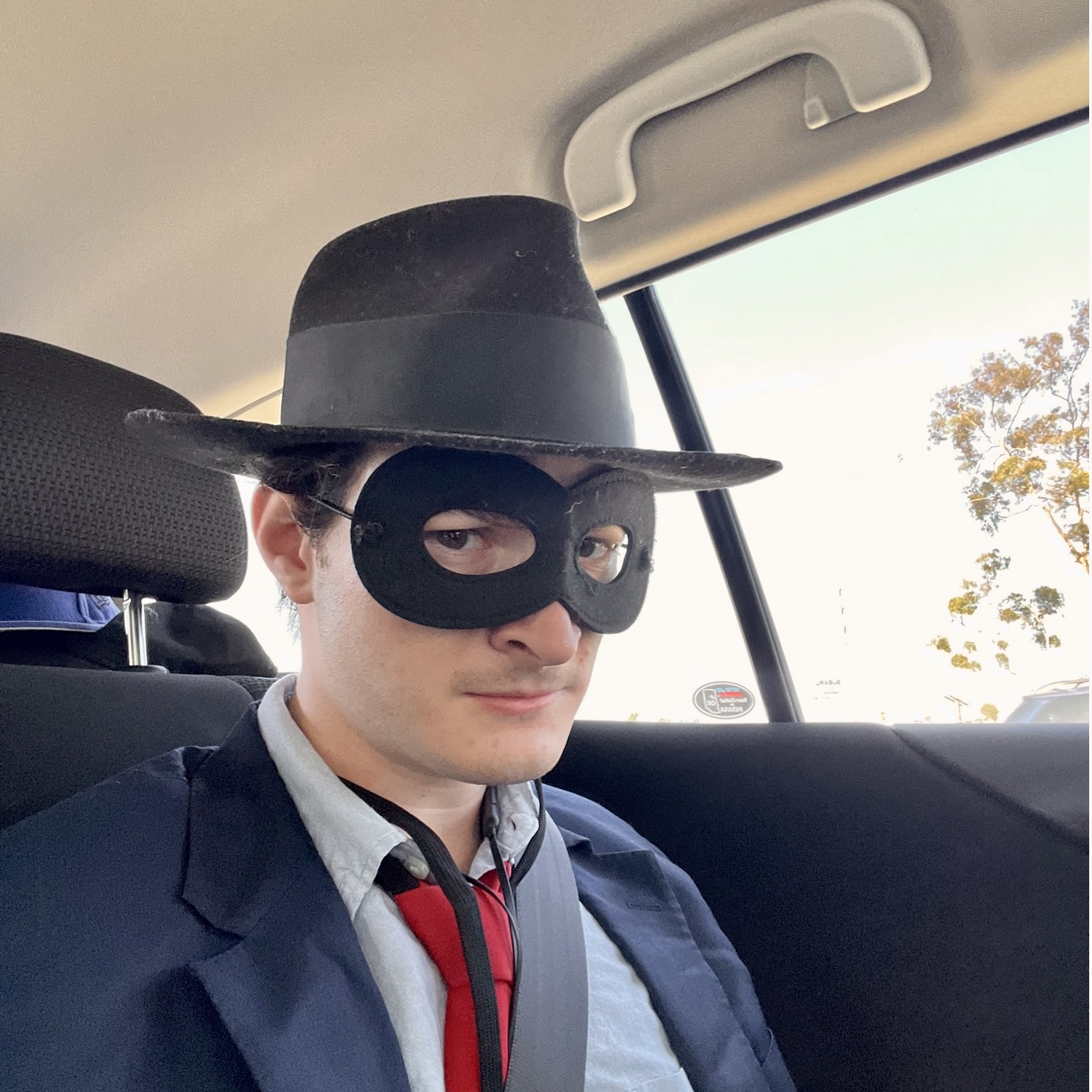 A photo of Erez wearing a black suit, red tie, and a cartoon superhero mask.